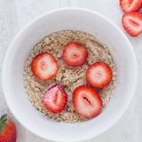 A bowl of oats topped with fresh strawberries